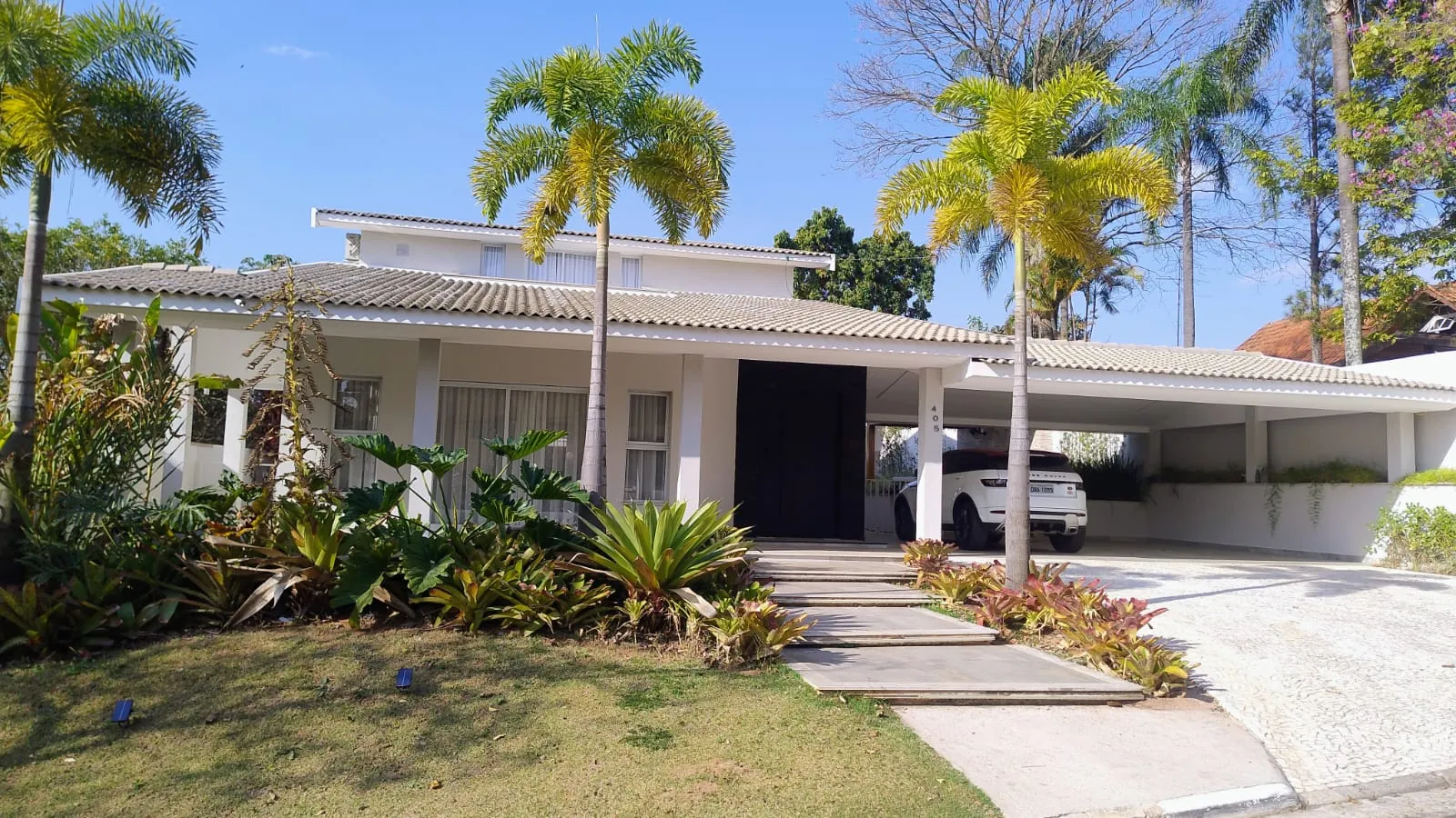 Residência com jardim de entrada, palmeiras e grama